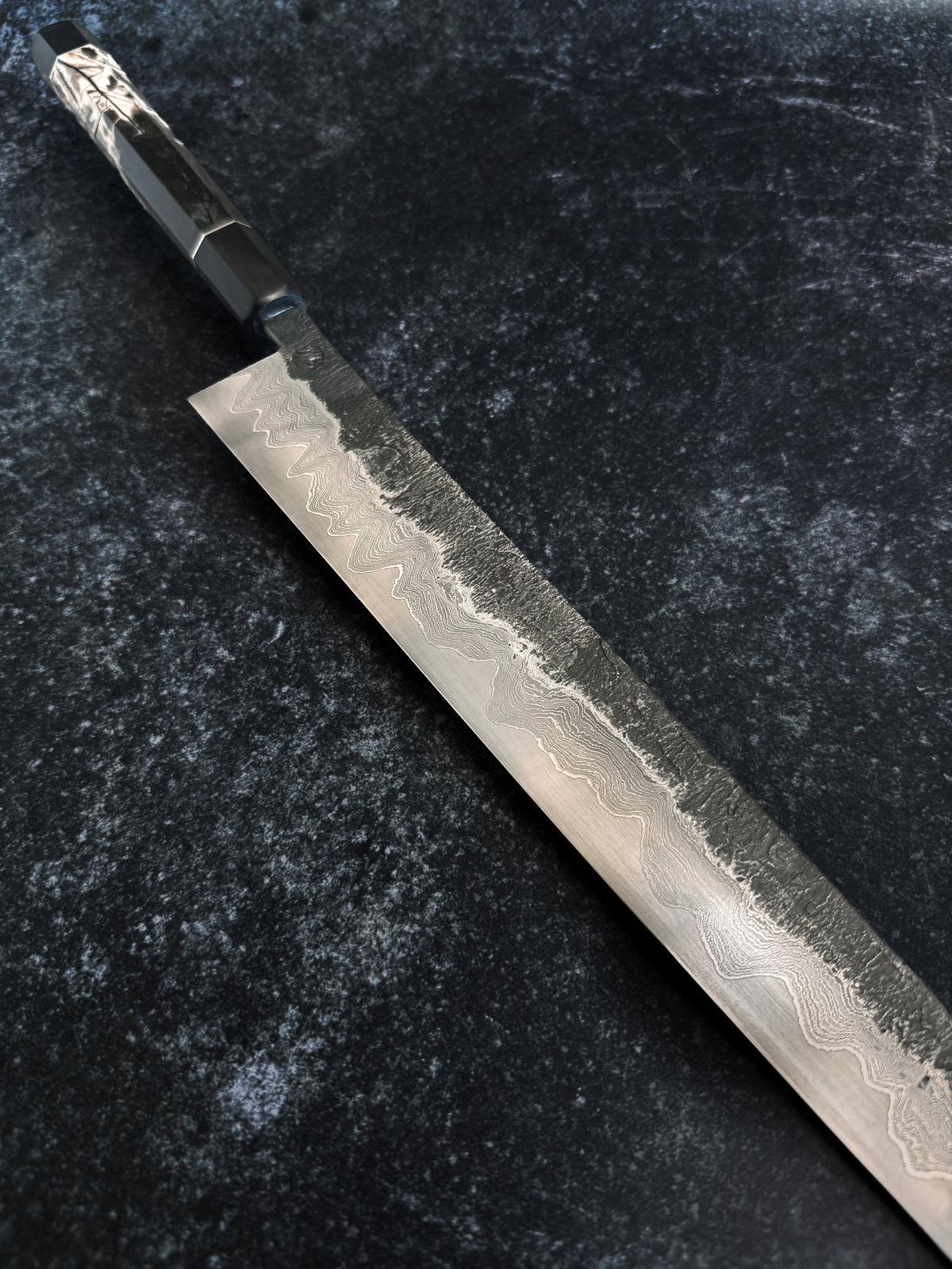 Close-up of hand-forged Damascus steel and a silver and African Blackwood handle